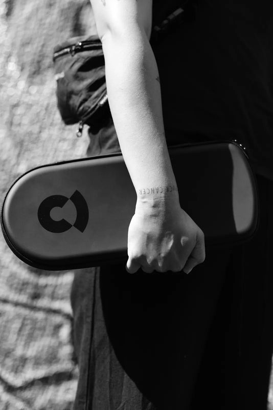 Schwarzweißfoto: jemand trägt das geschlossene Case unter dem Arm, das Coturn-Zeichen nach außen