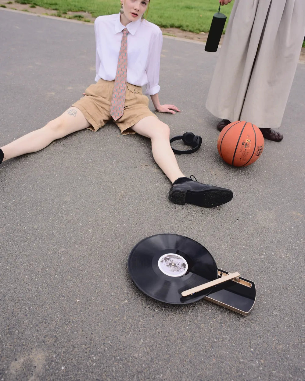 Eine Frau sitzt auf dem Asphalt, neben ihr ein Basketball und der CT-TWO mit aufgelegter Platte